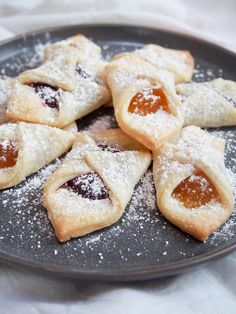 some cookies are sitting on a plate with powdered sugar and jelly in the middle