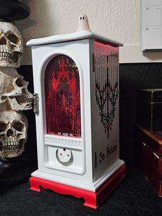 a white and red clock sitting on top of a table next to a pile of skulls