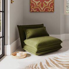 a green chaise lounge chair sitting in front of a large painting on the wall