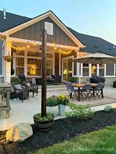 an outdoor patio with lights strung from the ceiling and seating area on the side of the house