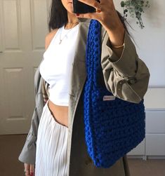 a woman is taking a selfie with her cell phone while wearing a blue crochet bag