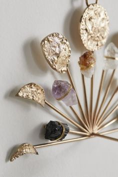 a bunch of different colored rocks on top of a white table next to a gold stick