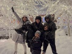 a group of people standing next to each other in front of a snow covered tree