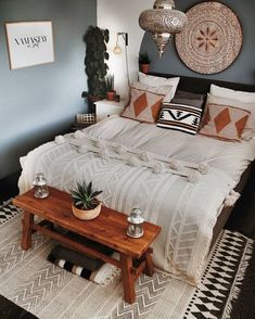 a bed sitting in a bedroom next to a wooden table with potted plants on it