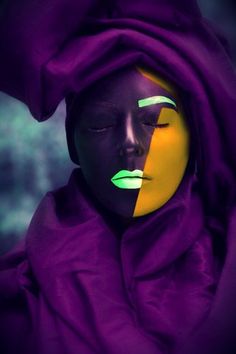 a woman's face is painted in yellow and purple with green eyeshades