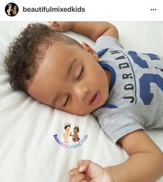 a small child laying on top of a white bed with his eyes closed and head resting on the pillow