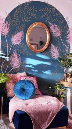 a bedroom with blue and pink walls, gold accents and a round mirror on the wall