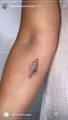 a woman's arm with a small tattoo of a seashell on the side