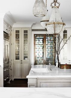 an open magazine showing a bathroom with chandelier, sink and cabinets in it