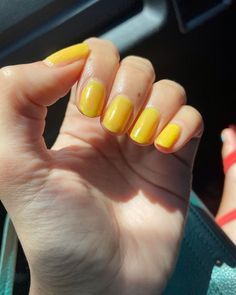 a woman's hand with yellow nail polish on it