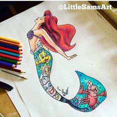 a drawing of a mermaid sitting on top of a table next to colored pencils