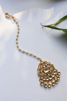 This beautifully handcrafted kundan based piece holding an exquisite detailed maang tikka in the centre is worked in gold plated silver alloy. The pearl strung chain add to the charm of the piece. Style Tip - This maang tikka is the go to accessory for a minimalistic yet regal look. With its simple, elegant design and delicate details, this one is for that effortless look. Versatility and elegance being the strong suit, we leave a lot to your imagination for how you want to dress your jewels you Elegant Ceremonial Tikka With Tilla Detailing, Gold Kundan Tikka With Cutdana, Elegant Meenakari Tikka For Festivals, Elegant Ceremonial Tikka For Navratri, Elegant Kundan Tikka With Zari Work, Elegant Kundan Tikka For Festivals, Festive Kundan Tikka For Ceremonial Occasions, Ceremonial Kundan Necklace With Stone Work For Eid, White Tikka With Latkans For Navratri