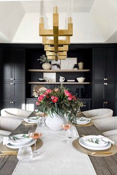 the dining room table is set with white plates and place settings, along with flowers