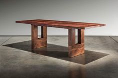 a wooden table sitting on top of a cement floor next to a white wall and grey walls