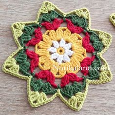 two crocheted flowers sitting on top of a wooden table