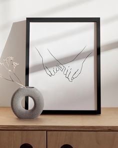 a vase sitting on top of a wooden table next to a framed photo with the word love written in cursive writing