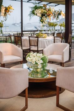 a room with chairs, tables and flowers on the table