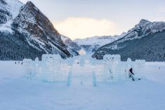 an ice sculpture in the middle of a snowy mountain range with people standing around it