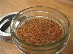 a glass jar filled with spices sitting on top of a wooden table next to a metal container