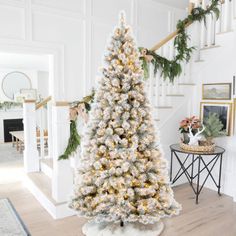 a decorated christmas tree in the middle of a living room with stairs leading up to it