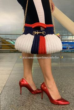 a woman wearing red, white, and blue shoes holding a handbag in her right hand