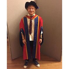 a man in a graduation gown standing next to a wall