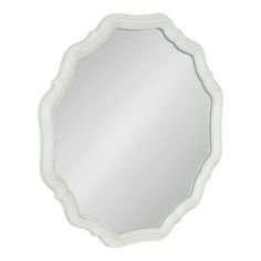 a white mirror with an ornate design on the top and bottom half, in front of a