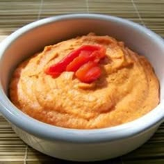 a white bowl filled with hummus on top of a bamboo place mat next to a knife