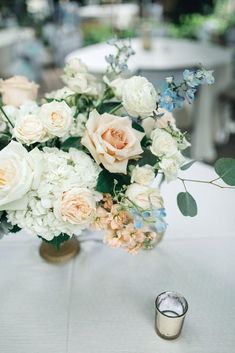 a vase filled with white and pink flowers on top of a table next to a candle