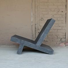 a concrete bench sitting in front of a brick wall