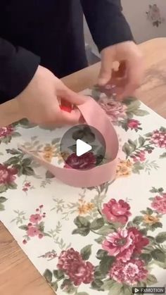 someone is making a flowered table runner with pink ribbon