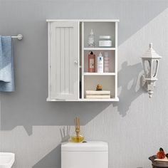 a bathroom with a toilet, cabinet and towel rack on the wall next to it