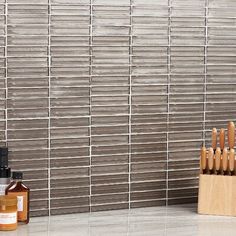 an assortment of kitchen utensils sitting in front of a tiled wall