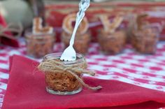 a spoon in a glass jar with some food inside it on a red table cloth