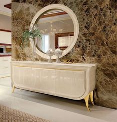 a white dresser sitting next to a wall with a round mirror on top of it