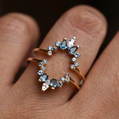 a woman's hand wearing a ring with blue and white stones on it,