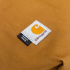 a label on the back of a brown shirt that says, earthpitt with an orange and white logo