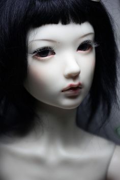 a close up of a doll with black hair and bangs on it's head