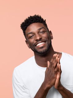 a man smiling and holding his hands together in front of him with both hands clasped