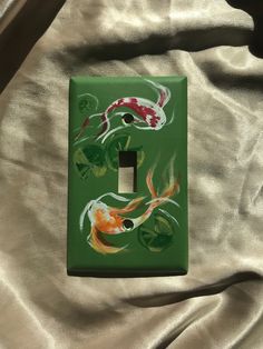 a green light switch cover with fish painted on it