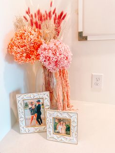 two vases filled with flowers and pictures next to a couple's wedding photo