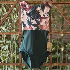 a bathing suit hanging on a wooden fence with plants in the backgroung