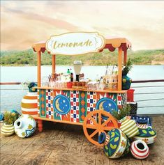 an ice cream cart with colorful decorations on the side and water in the back ground