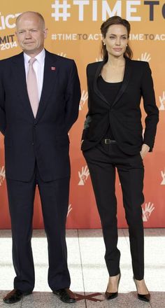 two people standing next to each other on a red carpet