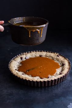 a person dipping sauce on top of a pie