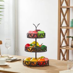 three tiered trays with fruit in them on top of a wooden dining table