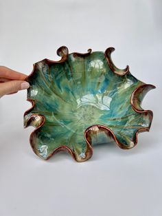 a hand holding a green and brown bowl