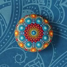 a painted rock sitting on top of a blue surface with an intricately designed design