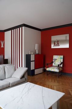 a living room with red and white walls, marble coffee table, and modern furniture