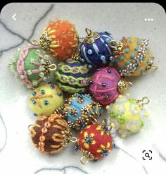 there are many different colored balls on the table together and one has a gold chain around it